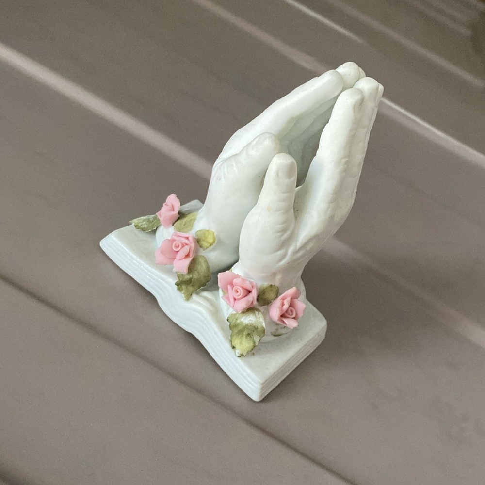 Vintage prayer hands over book and roses figurine